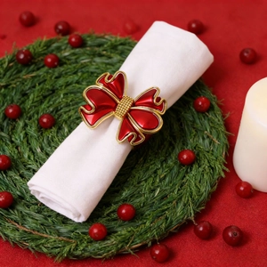Rond de serviette nœud de Noël rouge et doré sur serviette blanche avec couronne
