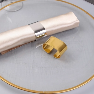 Gold and silver C-shaped metal napkin rings with mirror finish on glass tray