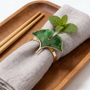 Golden ginkgo leaf napkin ring with green enamel on a grey linen cloth napkin