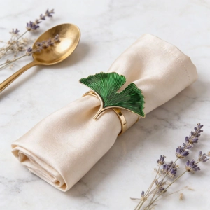 Elegant green enamel ginkgo leaf napkin ring with gold metal finish on marble table