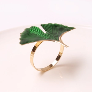 Detail of golden ginkgo leaf napkin ring with green enamel finish on cream background