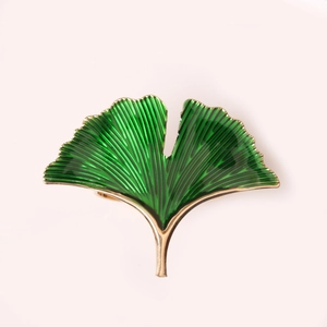 Macro detail of green enamel ginkgo leaf napkin ring with golden metallic edges