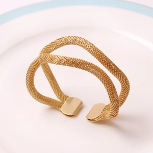Modern gold woven mesh napkin ring with elegant elastic double-layer design on a white plate