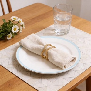 Elegant gold mesh spring napkin ring with double cross design on a dining table