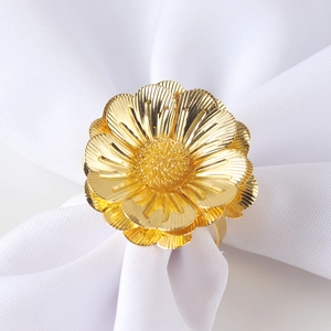 Elegant gold metal flower napkin ring on white fabric for hotel table decoration