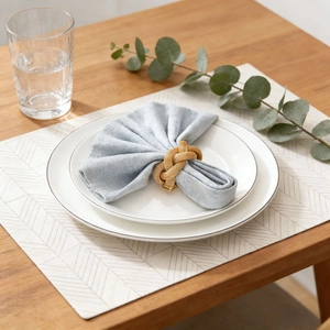 Golden woven mesh napkin ring with a spring knot design on a light blue napkin