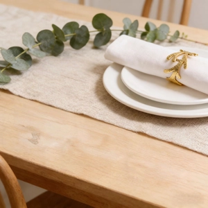 Detailed view of a golden branch-shaped napkin ring with hammer texture on a dining table
