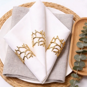 Golden coral branch metal napkin rings set on white linens for elegant table setting
