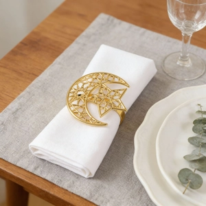 Elegant gold hollow crescent moon and star metal napkin ring on a white table napkin