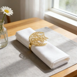 Golden hollow star and moon metal napkin ring on white linen with elegant table setting