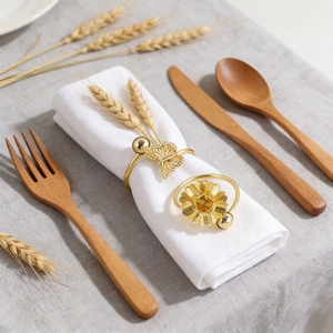 Golden butterfly and sunflower metal napkin rings set on white linen for table decor