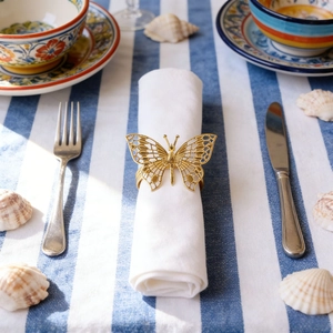 Goldener Serviettenring Schmetterling hohl auf blau gestreifter Tischdecke