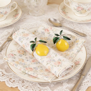 Elegant lemon napkin rings with green leaves on floral fabric for table decoration