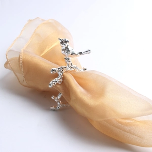 Close-up of bird and branch silver napkin ring on a golden mesh fabric napkin