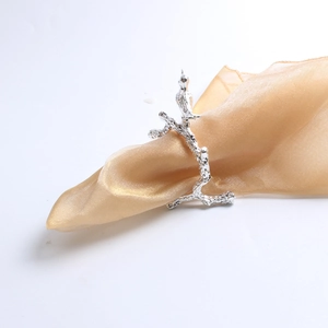 Macro detail of bird on a branch napkin ring in silver finish on a silk cloth