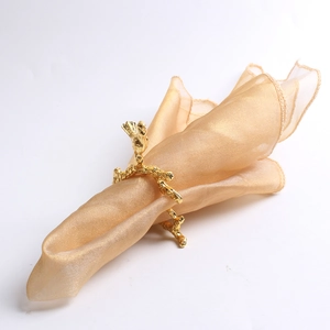 Elegant gold coral-shaped metal napkin ring with textured branch design on white background
