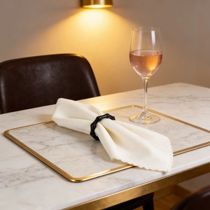 Elegante servilletero negro estilo bambú sobre tela blanca y bajoplato de mármol