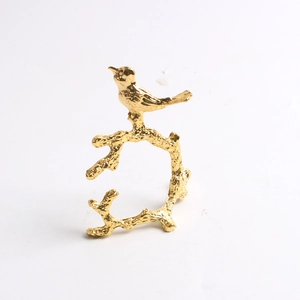 Golden bird on a branch napkin ring with lifelike metal texture on a white background