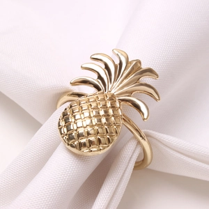 Close-up of golden pineapple napkin ring with textured finish on a white cloth