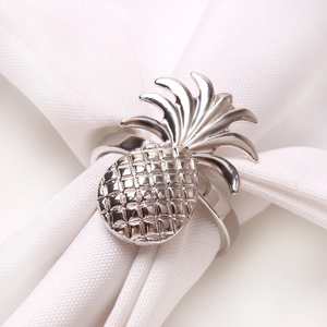 Polished silver pineapple napkin ring holder with detailed texture on white linen