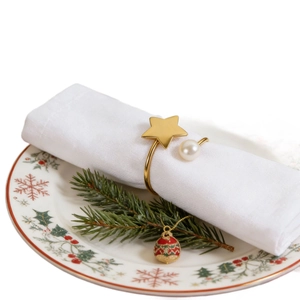 Golden star pearl napkin ring holder on festive plate with Christmas decor details