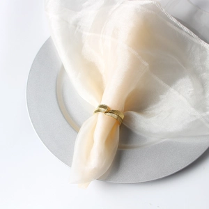 Detail of golden leaf napkin ring featuring fine leaf vein texture on a beige napkin