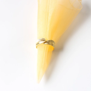 Macro view of gold feather napkin ring with detailed leaf vein texture on mesh fabric