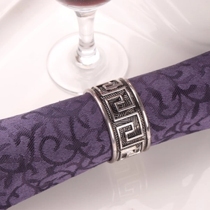 Rond de serviette en argent antique avec motif grec sur une serviette violette