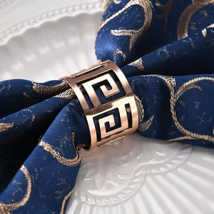 Elegant rose gold metal napkin ring with hollow geometric pattern on blue fabric