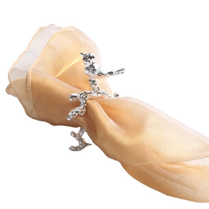 Silver bird shaped napkin ring on golden satin cloth with intricate feather carving details