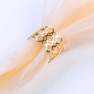 Close-up of golden hollow geometric napkin ring on champagne chiffon fabric