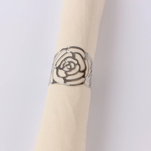 Detail shot of hollowed silver rose napkin ring on a beige linen fabric cloth