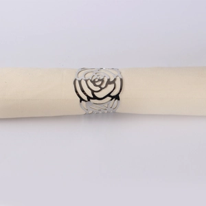 Close-up of a hollow rose napkin ring in polished silver finish on a beige cloth