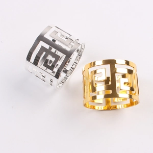 Detailed view of two metallic napkin rings with geometric Greek Key patterns in gold and silver
