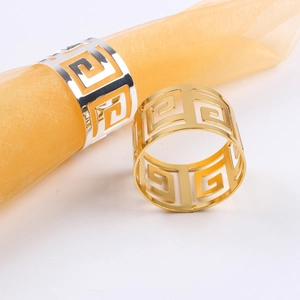 Detailed view of hollow gold and silver Greek key pattern napkin rings for table decor