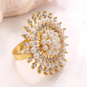 Gold sunflower ring with layered pearls and rhinestones on a white reflective surface