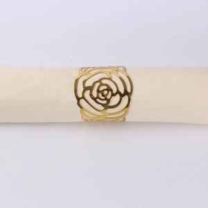 Close-up of a gold-plated rose napkin ring holder on a white folded linen napkin