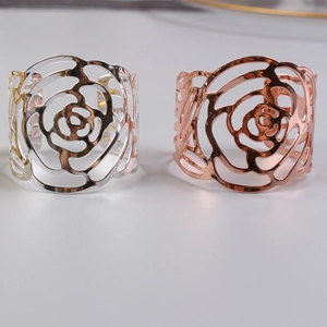 Detailed view of cutout rose napkin rings in polished silver and rose gold metal finishes