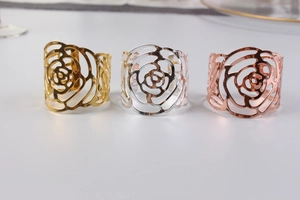 Close-up of hollowed-out rose flower napkin rings in gold, silver and rose gold metal