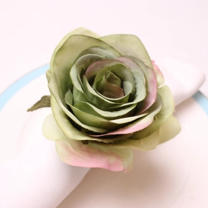 Close-up of pink artificial fabric rose napkin ring on a white plate with blue border