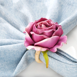 Elegant purple rose napkin ring with natural woven vine loop on light blue background