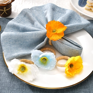 Close-up of four colorful artificial poppy flower napkin rings with woven straw bands