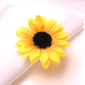 Detailed view of yellow sunflower napkin ring with brown center on white linen fabric