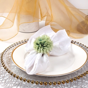 Macro view of green floral napkin ring on white textured fabric for wedding decor