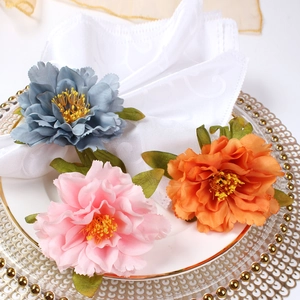 Detail of pink, blue, and orange floral napkin rings on a white plate with lace fabric