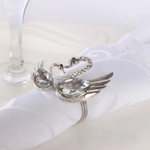 Elegant silver swan napkin rings with sparkling rhinestones set on white embroidered linens