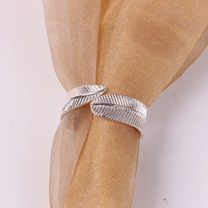 Silver feather wrap open ring with detailed texture on elegant golden fabric background