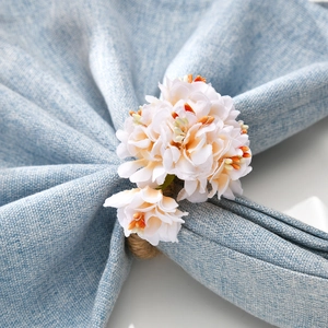 Macro detail of artificial sunflower napkin ring with white petals and rustic hemp rope loop