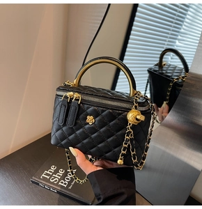 Detail of black quilted leather handbag with gold camellia clasp and chain strap