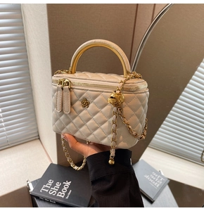 Detail of cream quilted leather box bag with golden camellia logo and chain strap